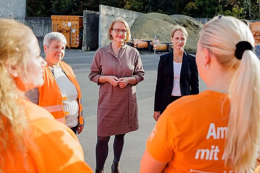 Lisa Paus und Prof. Dr. Marcel Fratzscher stehen in einem Kreis zusammen mit Mitarbeiterinnen der Berliner Stadtreinigung