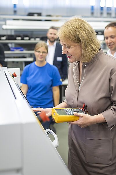 Lisa Paus bei bei IMM electronics, im Hintergrund drei Personen 