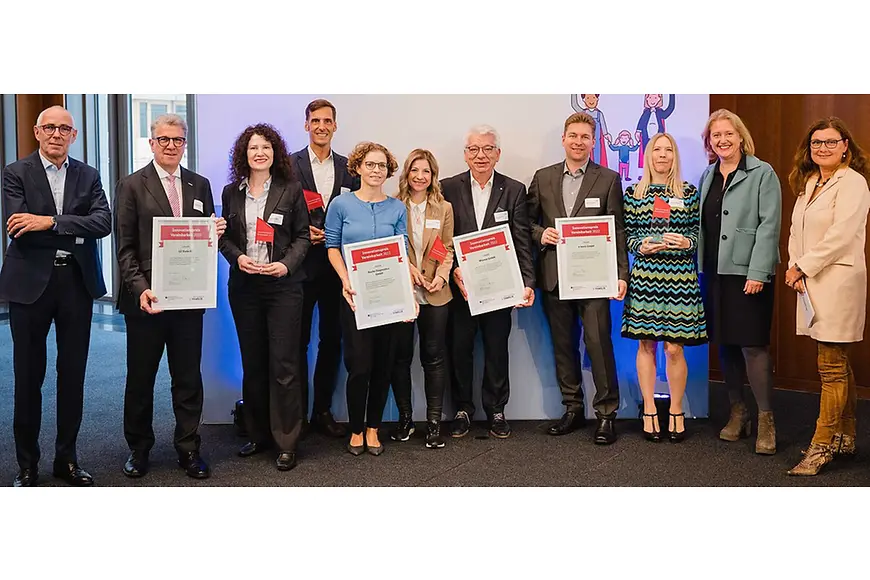 Eine Gruppe von Menschen, alle schauen in die Kamera, einige halten eingerahmte Urkunden in der Hand