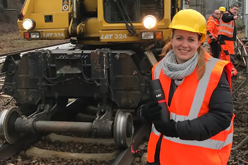 Tamara Gross steht vor einer Baustelle für Schienenarbeiten.