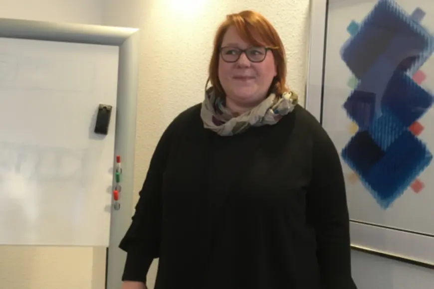 Eine Frau steht vor einem Whiteboard und schaut zur Seite