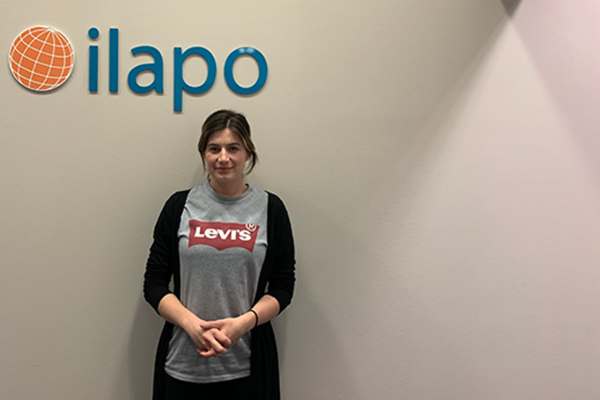 Eine Frau vor einer Wand mit einem Logo mit Text "ilapo"