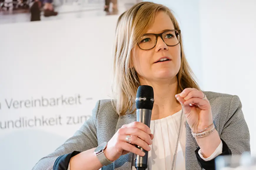 Eine Frau sitzt und hält ein Mikrofon in der Hand