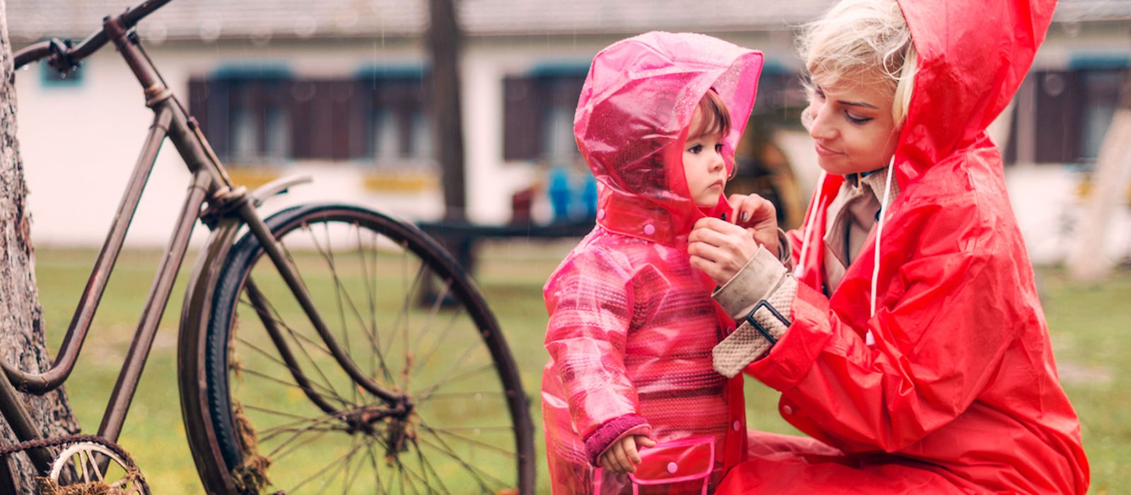 Eine Mutter zieht ihrer Tochter Regenjacke über.