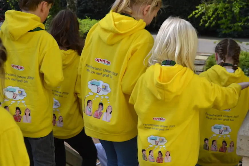 Kinder von hinten mit gelben Pullovern