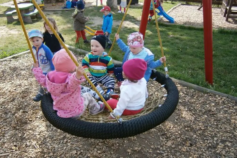 Vier Kinder sitzen auf einer großen Schaukel