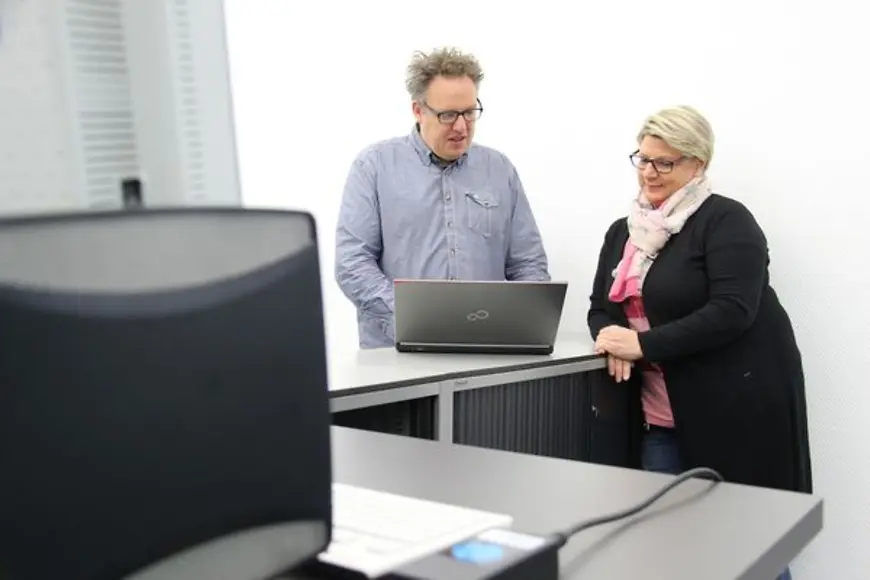 Ein Mann zeigt einer Frau etwas auf einem Laptop