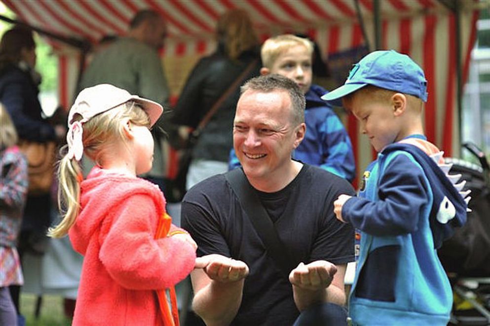 Ein Mann kniet, links und rechts von ihm zwei Kinder