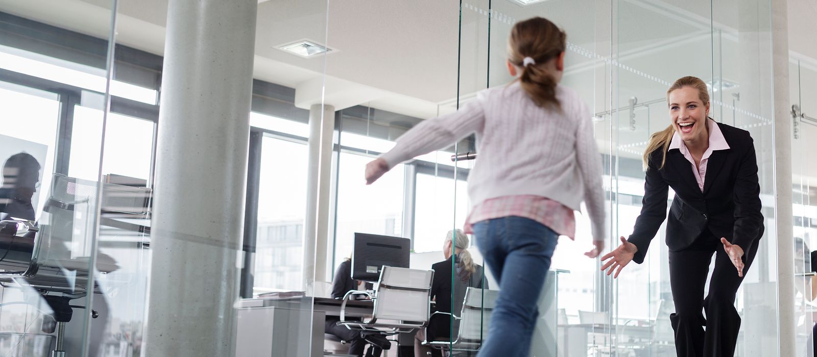 Ein Kind rennt auf eine Frau in einem Büro zu.