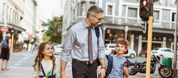 Ein Mann und zwei Kinder laufen Hand in Hand über die Straße
