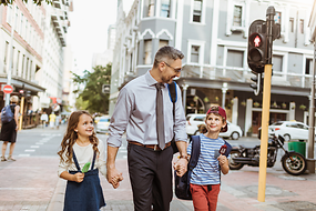 Ein Mann und zwei Kinder laufen Hand in Hand über die Straße