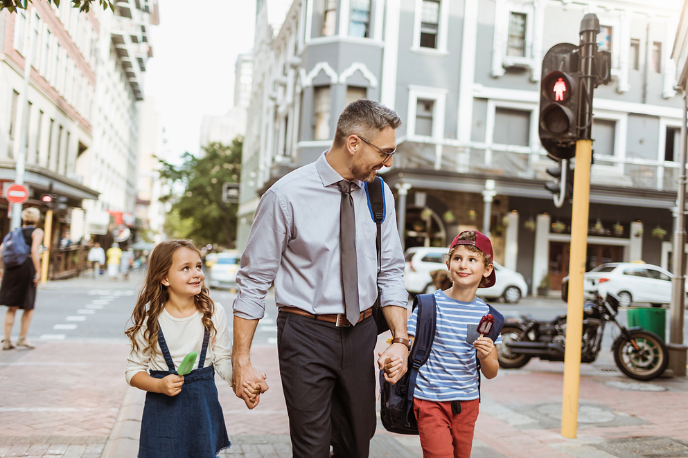 Ein Mann und zwei Kinder laufen Hand in Hand über die Straße