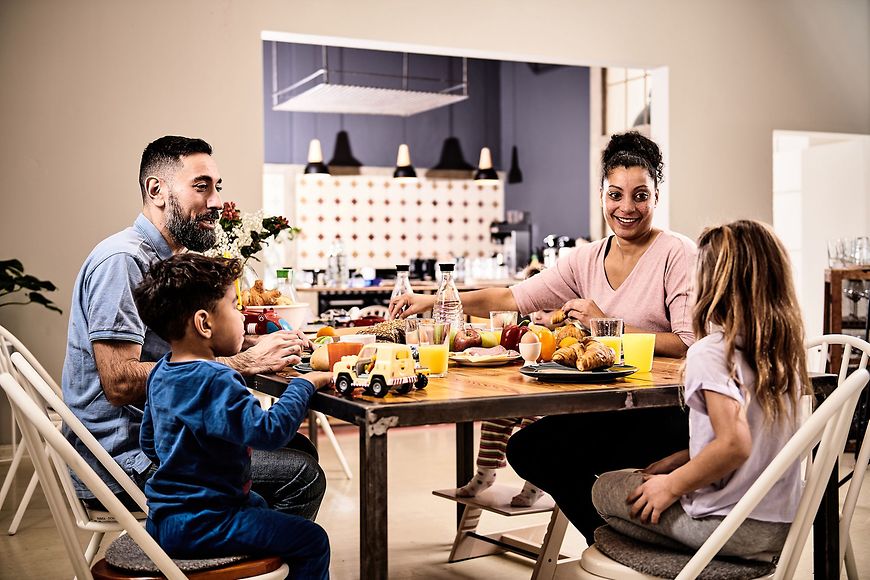 Eine Familie mit zwei Kindern sitzt am Küchentisch.