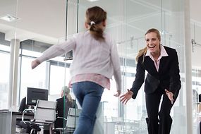 Ein Kind rennt auf eine Frau in einem Büro zu.