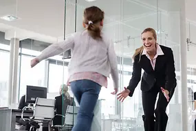 Ein Kind rennt auf eine Frau in einem Büro zu.