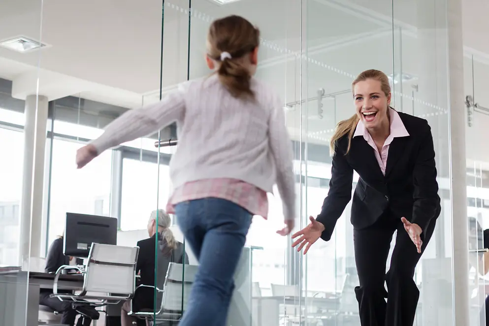 Ein Kind rennt auf eine Frau in einem Büro zu.
