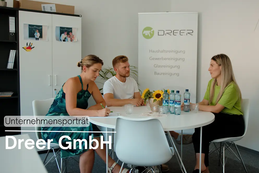 Drei Personen sitzen an einem runden Tisch im Büro der Dreer GmbH und beraten sich..