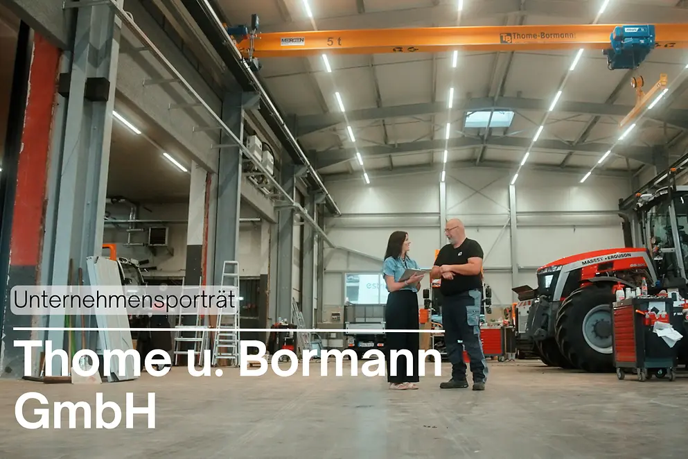 Eine Frau und eine Mann unterhalten sich in einer Lagerhalle. Im Hintergrund steht ein Traktor.